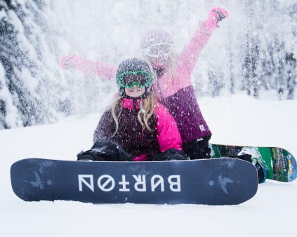 Barn som åker snowboard och leker i snön.