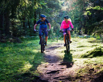 Bild på två personer som cyklar i skogen